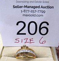 Gold tone ring size 6 displayed below auction lot card, showing clear gemstones in a single row on a curved band.