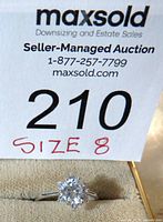 Photo of ring and auction tag showing size 8 and lot number 210.