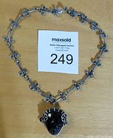 Full view of the necklace laid flat showing the linked silver chain and face pendant.