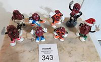 Nine vintage California Raisins figures including a Michael Jackson themed raisin figure held in hand and standing on marble surface