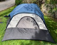 Wenger tent fully set up showing front door with blue rainfly and black bottom panels on grass outdoors.