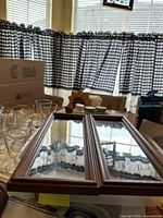 Two rectangular wood framed mirrors with dark brown finish laid on table.