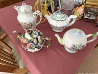 Four assorted ceramic teapots arranged on table, showing shapes, colors, and designs