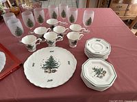 All items including dessert plates, saucers, cups, stemware glasses, and a large party plate featuring the Christmas tree pattern