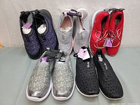 Five pairs of new ladies running shoes arranged in two rows showing colors and styles