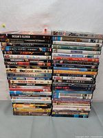 Two columns of assorted DVD movies stacked on a carpeted floor.