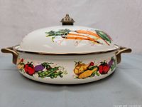 Side view of 10-inch enamel on steel covered buffet server with vegetable motif and brass-tone side handles.