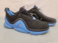 Side view of Jordan Trunner sneakers showing black upper and blue sole with white Jumpman logo