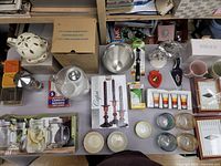 Full assortment of kitchen and home items arranged on table showing teapot, glassware, candles, and other accessories