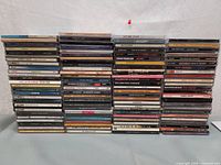 Wide view of approximately 70 music CDs stacked in five columns showing a mixed genre English music CD collection.