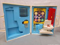 Open case showing microscope, compartments for slides, tweezers, and guide book with colorful images.