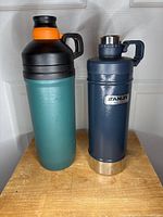 Two Stanley thermos bottles standing upright, showing front and side profiles.