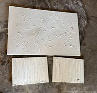 Three white textured wall decor pieces, one large and two smaller rectangular, displayed on floor. One small piece shows chip damage.