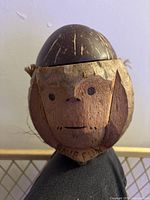 Front view of carved coconut monkey head showing detailed painted face and texture.
