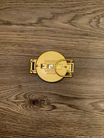 Top-down view of compact yellow metal engineer directional compass with foldable side arms.