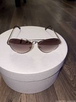 Juicy Couture sunglasses with butterfly-shaped gradient lenses on Dior box, showing front view