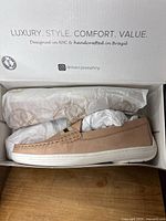 Side profile view of new men's loafer in box showing textured light tan leather and white sole.