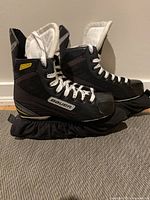 Side view of the black Bauer Supreme Pro ice hockey skates showing the design and condition.