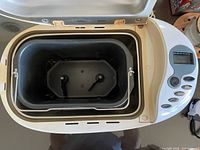 Top view inside the bread maker showing the removable bread pan and two kneading paddles.