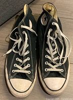 Front view of both black Converse shoes showing white rubber toe caps and laces.