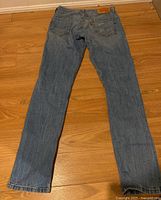 Full back view of light blue Levi's 511 jeans laid flat on wooden floor, showing straight fit and overall condition.