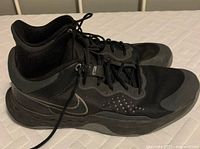 Side view of black Nike running shoes showing mesh and synthetic upper, Nike swoosh logo, and worn condition.