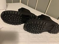 Photo showing the thick, heavily treaded rubber soles of the black men's winter boots to highlight traction and waterproof features.