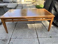 Front and angled view of mid-century coffee table showing tapered legs and inset wooden top.