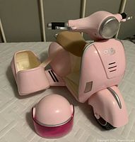 Front and side view of the pink motor bike toy with attached sidecar and separate pink helmet placed near it.