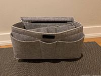 Front view of grey felt handbag organizer insert showing three exterior pockets and overall rectangular shape.