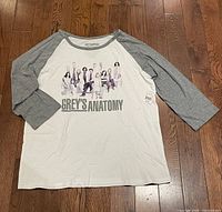 Front view of Grey's Anatomy raglan sleeve shirt with cast print in white and gray