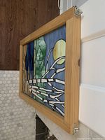 Side angle showing the wood frame and depth of stained glass panel, with metal hooks for hanging.
