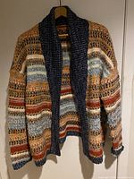 Front view of large multi-colored knit cardigan with dark collar on hanger