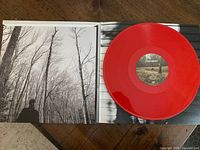 Open gatefold view showing black and white photo of Taylor Swift in woods on left and one red vinyl record on the right side.