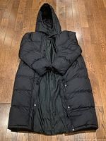 Front inside view of the black full-length winter coat showing interior lining and snap closures