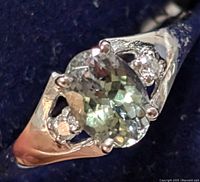 Close-up front view of oval tanzanite gemstone with two smaller diamond accents in 10KT white gold ring.