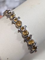Close-up side view of silver and citrine bracelet showing alternating round and square stones and silver flourishes.