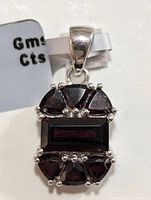 Close-up image of silver pendant with rectangular and triangular garnet stones, focused on top view.