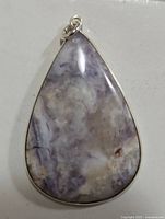Front view of the teardrop-shaped genuine gemstone pendant set in silver with visible marbling and silver bail.