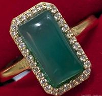 Close-up front view of silver ring with rectangular green onyx center stone and surrounding cubic zirconia stones.