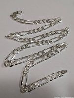 Close-up of the silver chain laid flat showing clad links and lobster clasp with hallmark stamp.