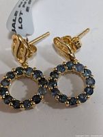 Front view of the gold-tone silver earrings showing the circular hoop studded with blue sapphires.