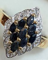 Close-up front view showing marquise-cut blue sapphires and clear stones cluster setting in two-tone silver and gold metal.