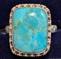 Close-up of rectangular turquoise stone set in silver ring showing natural color variations and matrix.