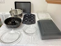 Overview of variety of metal and glass baking pans, including Bundt, angel food cake, mini bagel, multiple Pyrex casserole dishes, pie plates, and metal baking sheets.