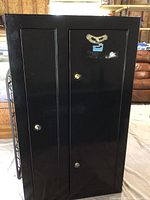 Front exterior view of black Homak cabinet showing double doors, lock positions and Homak logo decal