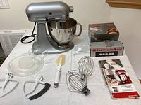 Overview of mixer, bowl, attachments, spatula and boxed attachments on table