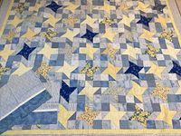 Full view of quilt laid flat showing blue and yellow star patchwork pattern