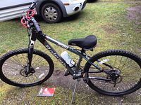 Side view of Raleigh M80 mountain bike showing frame, seat, tires, water bottle, and cable lock on ground.