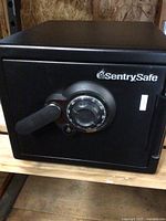 Exterior front view showing black steel body, combination dial and pull handle, SentrySafe logo